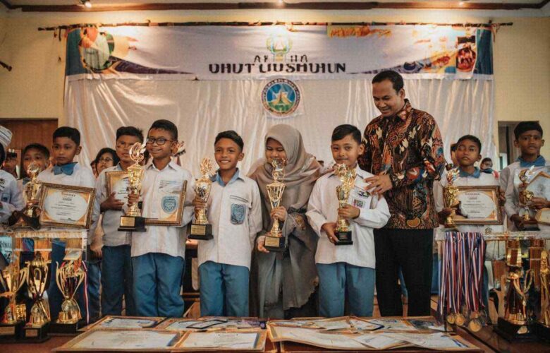 Siswa SD Islam berprestasi di Jogja sedang menerima piala penghargaan lomba dari guru dengan bangga di sekolah